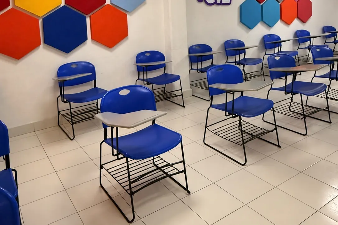 Salón de la sede Roma Sur de #cursoCIE con pupitres azules y paneles hexagonales de colores en la pared